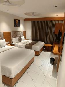 Una habitación de hotel con dos camas y un televisor. en Hotel Peceful Villa, en Ahmedabad