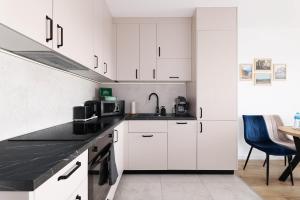 a kitchen with white cabinets and a black counter top at Apartament Brzeziny by Stay&Rest - szybki dojazd i parking in Czechowice-Dziedzice