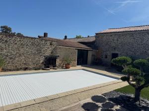 a swimming pool in front of a stone building at Gîte L'Apothicaire in Montaigu-Vendée