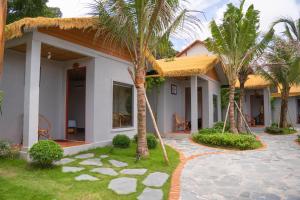 a house with palm trees in front of it at Forest Home Phu Quoc is located beside the forest and on a hillside in Phú Quốc