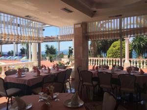 una sala da pranzo con tavoli, sedie e finestre di Hotel Dodona a Sarandë