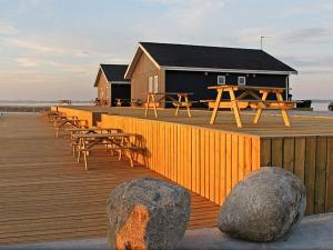 ein hölzerner Steg mit Tischen und Stühlen und ein Gebäude in der Unterkunft 10 person holiday home in Vinderup-By Traum in Vinderup