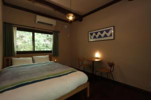 a bedroom with a bed and a window and a table at 阿蘇山麓のヴィラShijin南阿蘇 in Minami Aso