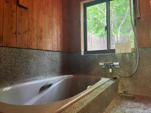 a bath tub in a bathroom with a window at 阿蘇山麓のヴィラShijin南阿蘇 in Minami Aso +37 photos
