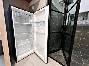 an empty refrigerator with its door open in a kitchen at Modern 2-Bedroom Escape in Kuching