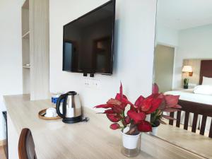 a room with a tv and a table with flowers at Alana Seaview by CKV - Free Airport Pick Up in Phu Quoc
