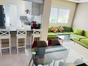 a living room with a green couch and a kitchen at Fal azure in Bouznika
