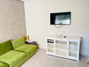 a living room with a green couch and a flat screen tv at Fal azure in Bouznika