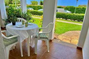un tavolo bianco e sedie su un portico di SON BOU Apartamento en planta baja junto la playa a Son Bou