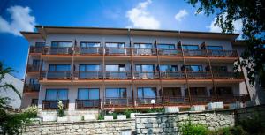 an apartment building with balconies and a stone wall at Bisser Hotel - Free Parking - Free Pool Access in Balchik