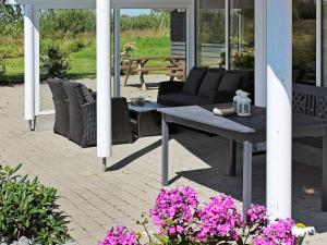 a patio with a bench and a table and flowers at Luxury Retreat with Spa - By Traum Ferienwohnungen in Marielyst