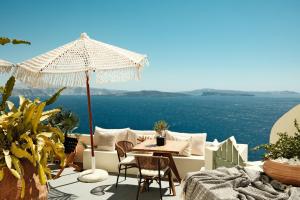 a patio with an umbrella and a table and chairs at Anemos Caldera Oia in Oia