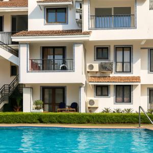 an apartment building with a swimming pool in front of it at Riviera Hermitage Luxury Apartment in Anjuna