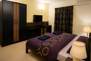 a bedroom with a purple bed and a television at Riviera Hermitage Luxury Apartment in Anjuna