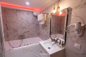 a bathroom with a sink and a tub and a mirror at Touraco in Villars-les-Dombes