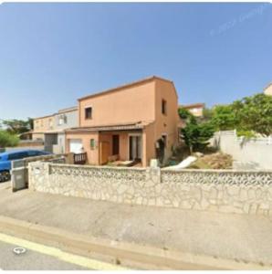 ein Haus mit einem Steinzaun vor einem Gebäude in der Unterkunft Maison sur vue montagne in Canet-en-Roussillon