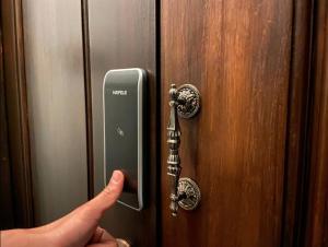 a hand is pressing a key on a door at Charoen Hostel in Chanthaburi