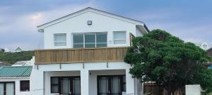 a white house with a wooden balcony on top of it at Audrey Hepburn Suite Yzerfontein in Yzerfontein