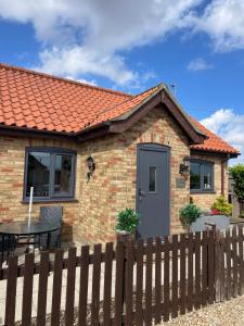 a brick house with a table and a fence at Oxley Cottage in Alford