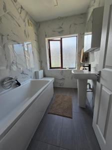 Un baño blanco con bañera y lavabo. en Selene Apartment in Heart of Glastonbury, en Glastonbury