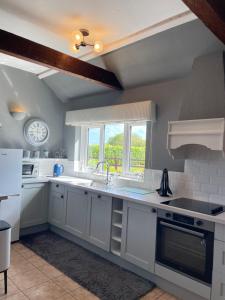 a kitchen with white cabinets and a sink and a window at Oxley Cottage in Alford