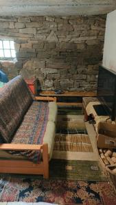 a living room with a couch and a stone wall at Horská Roubenka Emma in Čierne