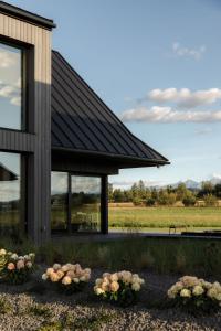 a house with a black roof and some flowers at Baniska Houses jacuzzi oraz sauna w cenie in Szaflary