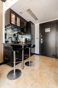 una cocina con armarios negros y un bar con taburetes en Luxury Suite - 3 Min Walk to Miami Beach, en Miami Beach