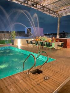 a swimming pool with a table and a fountain at Hôtel Saphir Group in Douala