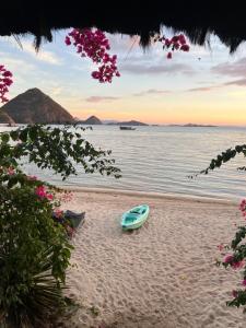 un barco sentado en una playa con el océano en Waecicu Eden Beach Hotel, en Labuan Bajo