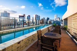 a balcony with a pool and table on a building at Carnaval com conforto e vista incrível - Studio com rooftop, piscina vista mar e academia in Salvador