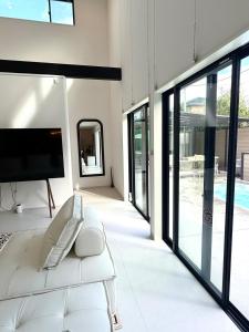 a living room with a white couch and a tv at Sunshine pool villa 2新築ラグジュアリーリゾートヴィラ天然芝ゴルフサウナ完備 in Katakai