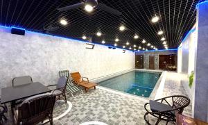 Una piscina con una mesa y sillas al lado. en Mubina East Hotel, en Bukhara