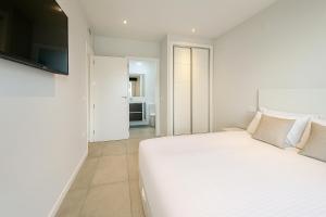a white bedroom with a white bed and a television at Lucerna II, Bajo 2 in Dehesa de Campoamor +21 photos
