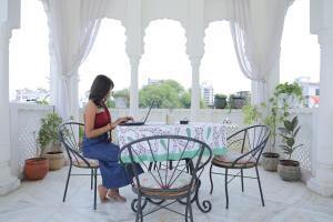 a woman sitting at a table with a laptop at Otla - A Heritage Boutique Hotel, Jaipur in Jaipur