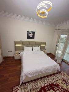 ein Schlafzimmer mit einem großen weißen Bett und einem Kronleuchter in der Unterkunft فيلا مع حمام سباحه وحديقه 0306-888-0106 in Kairo