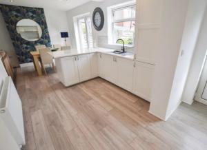 a kitchen with white cabinets and a wooden floor at Coastal Corporate Stays in Blythe