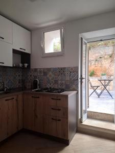 une cuisine avec un évier, une fenêtre et une table dans l'établissement La Dimora Sicula, à Modica