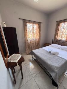 a bedroom with a bed and a chair and two windows at PANKO Suite in Dhímitra