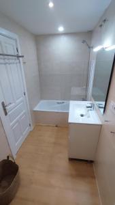 Un baño con bañera, lavabo y espejo. en El Llano Descanso, en Escarrilla