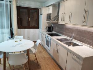 cocina con mesa, mesa blanca y sillas en El Llano Descanso, en Escarrilla