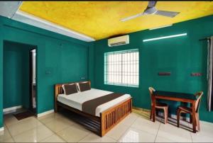ein Schlafzimmer mit grünen Wänden, einem Bett und einem Stuhl in der Unterkunft White Clouds Inn in Ernakulam