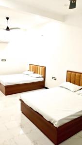 three beds in a room with white walls at Aakriti's Home Stay in Jāmb