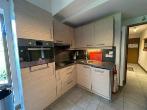 une cuisine avec des armoires en bois et un comptoir dans l'établissement Appartement charmant à Morillon, proche du lac et navette, avec terrasse et équipements modernes - FR-1-642-88, à Morillon 11 autres photos