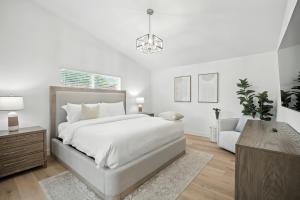 una camera da letto bianca con un letto e una sedia di Sunny Desert Retreat Near Coachella & Stagecoach home a Desert Groves Mobile Home Park