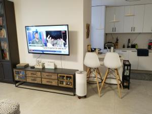a living room with two white chairs and a tv at Rony's Place in Ashkelon