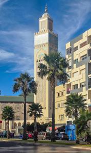 a tall clock tower with palm trees in front of a building at Apartment Casa Marina - Borgone, Ocean & Hassan II Views in Casablanca