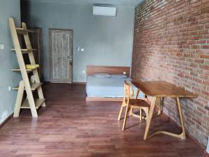 a room with a brick wall and a desk and a bed at Kirana rooms in Kerobokan