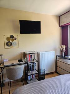 a bedroom with a desk and a tv on the wall at Idéal long séjour, Souvenirs de Provence,T2 classé, vue sur les montagnes, toutes commoditées! in Digne-les-Bains
