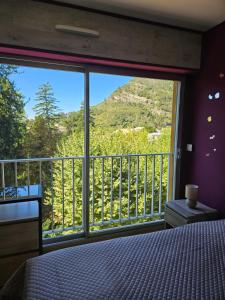 a bedroom with a large window with a mountain view at Idéal long séjour, Souvenirs de Provence,T2 classé, vue sur les montagnes, toutes commoditées! in Digne-les-Bains